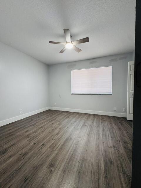 Empty bedroom with wood-look flooring, a ceiling fan, and a window with a closed blind.