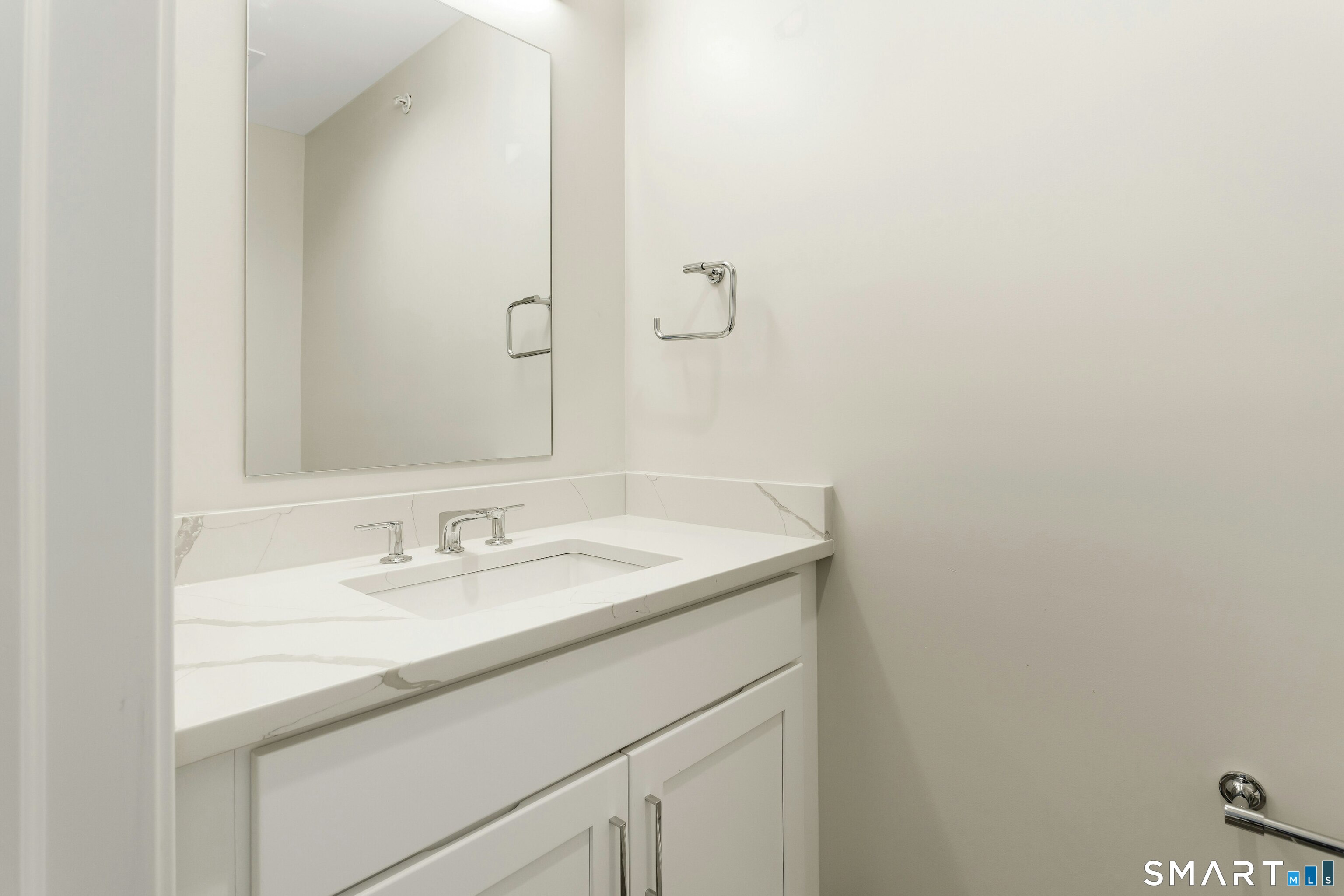 Modern bathroom vanity with a veined white countertop, integrated sink, and large mirror.