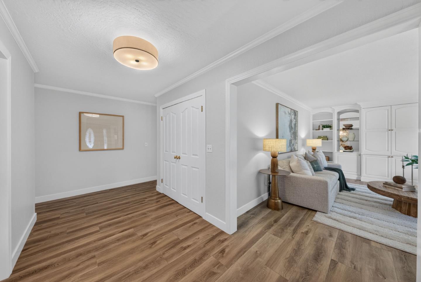 Wood-floored entryway opening into a living room with a pale sofa and built-in white cabinetry.
