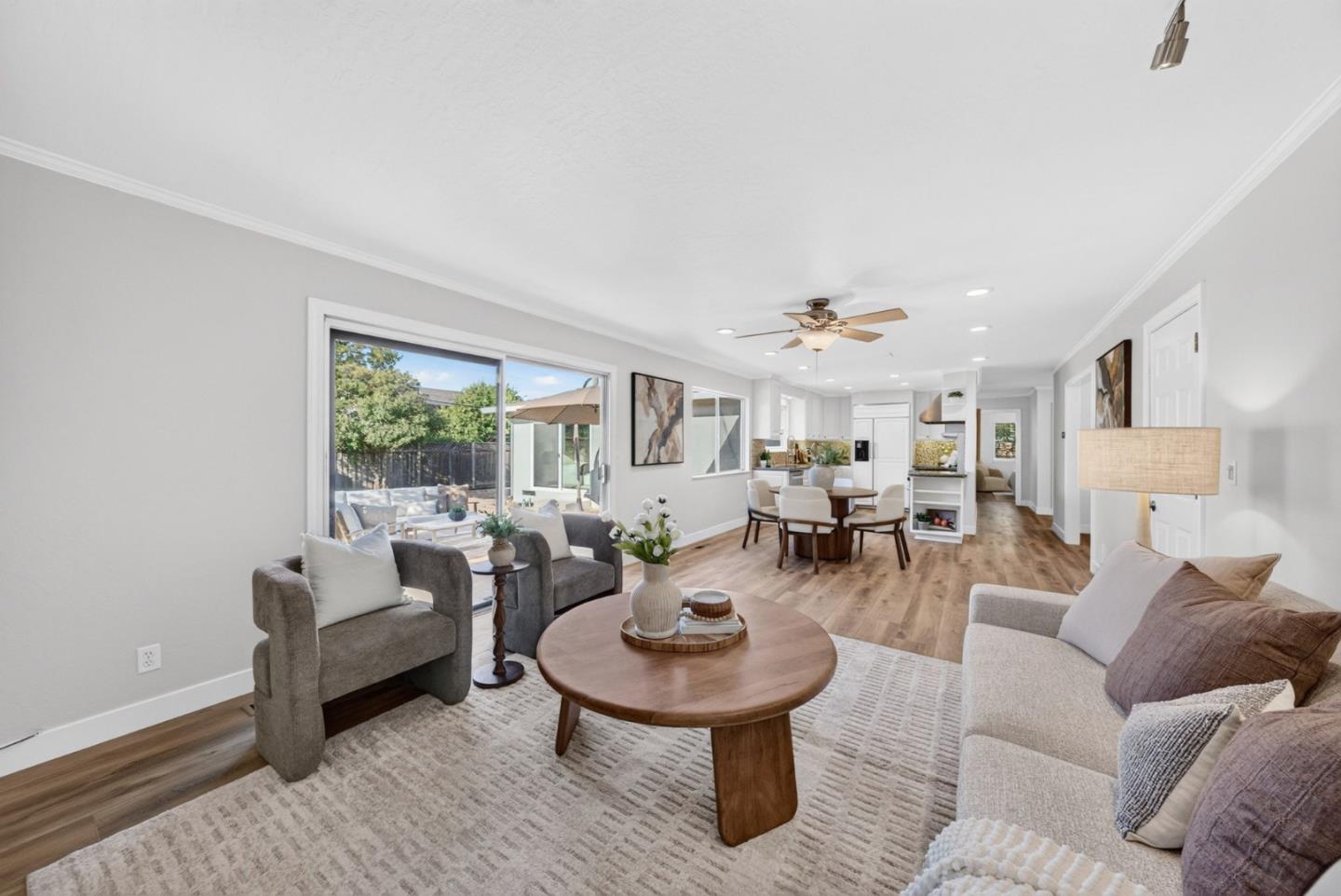 Open-plan living room with neutral seating, a wood coffee table, and sliding doors to a patio.
