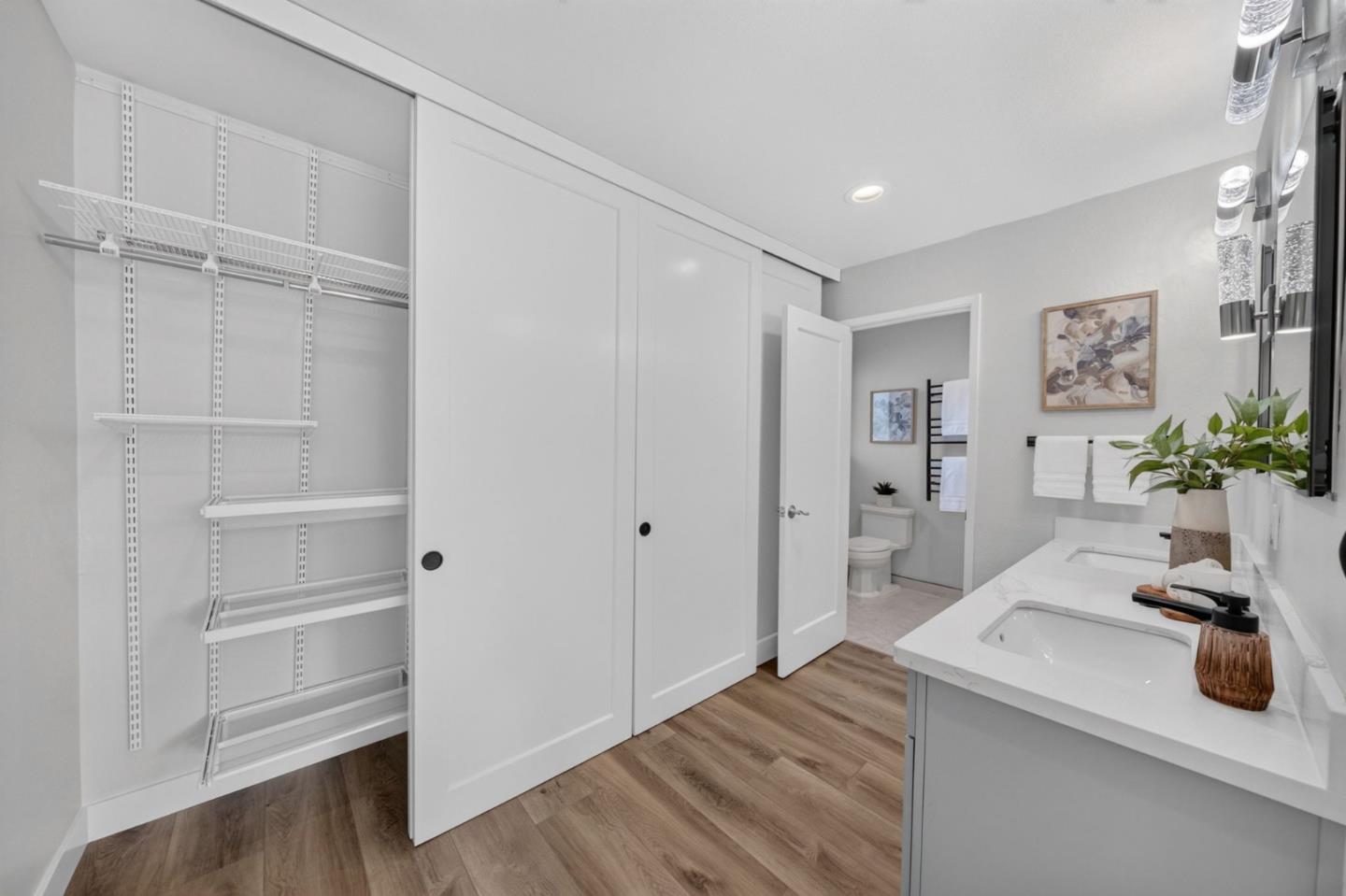 Remodeled bathroom with white vanity and open adjustable-shelf closet beside the doorway.