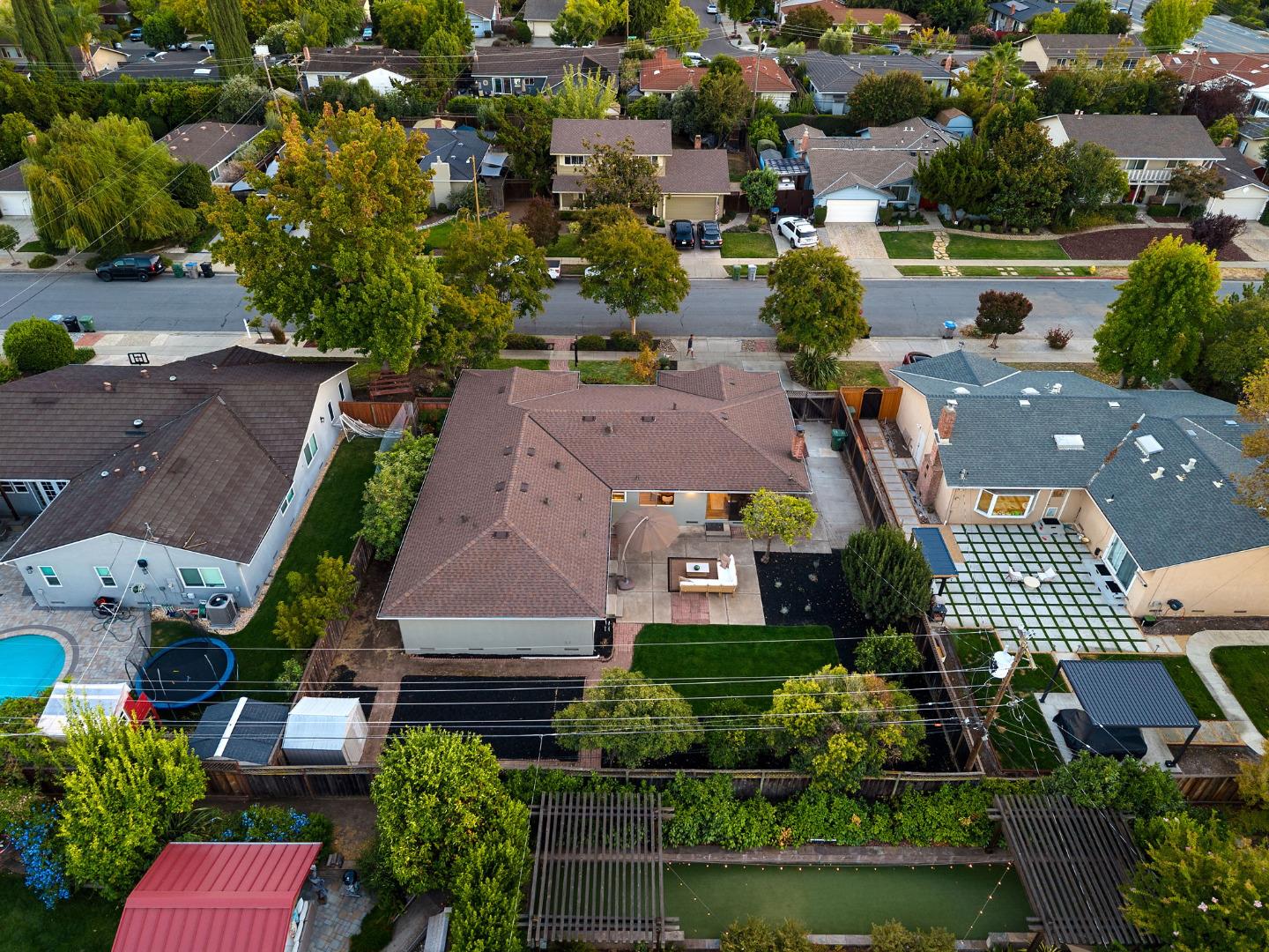 Aerial view of a landscaped backyard with a patio, lawn, and pergola.