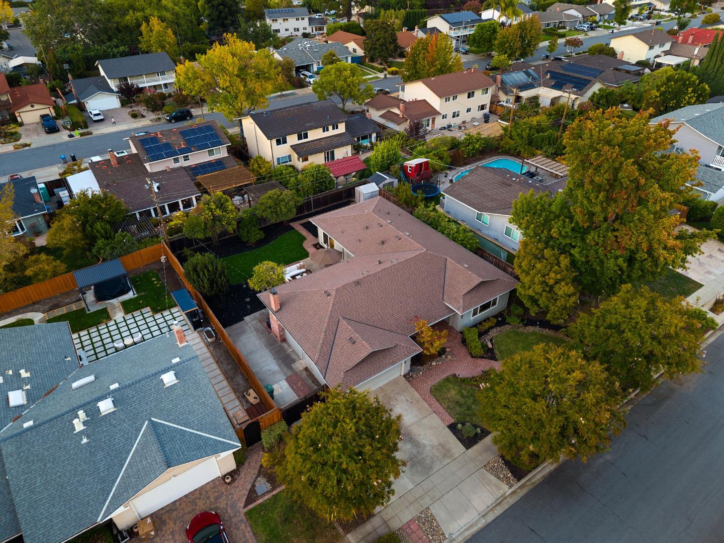 Aerial view of a single-story San Jose home with a tile roof, fenced yard, and mature trees.