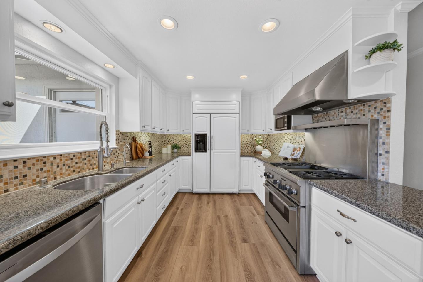 Kitchen with white cabinets, granite counters, mosaic backsplash, and stainless steel appliances.