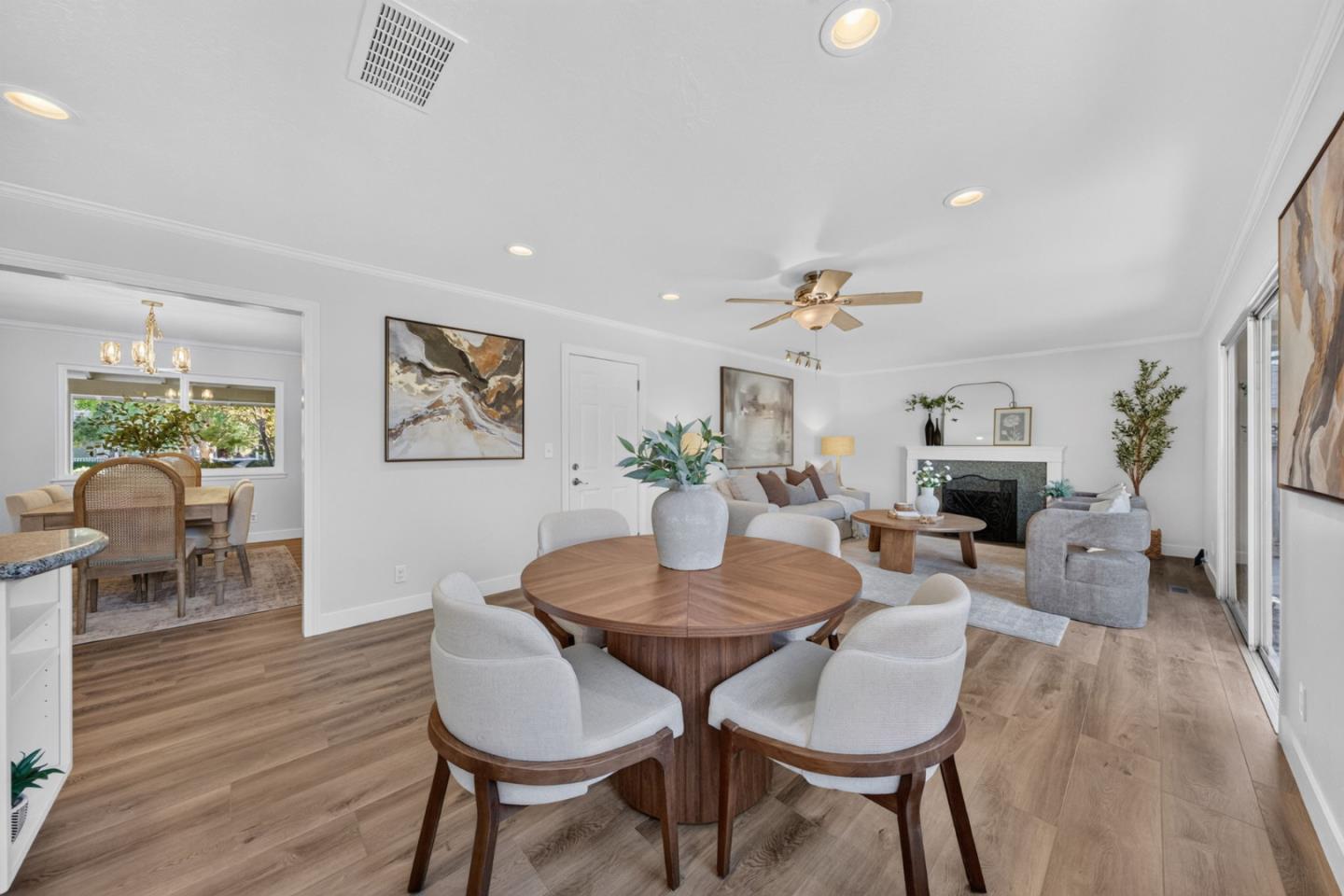 Open-plan living and dining room with a round wood table, gray seating, and fireplace.