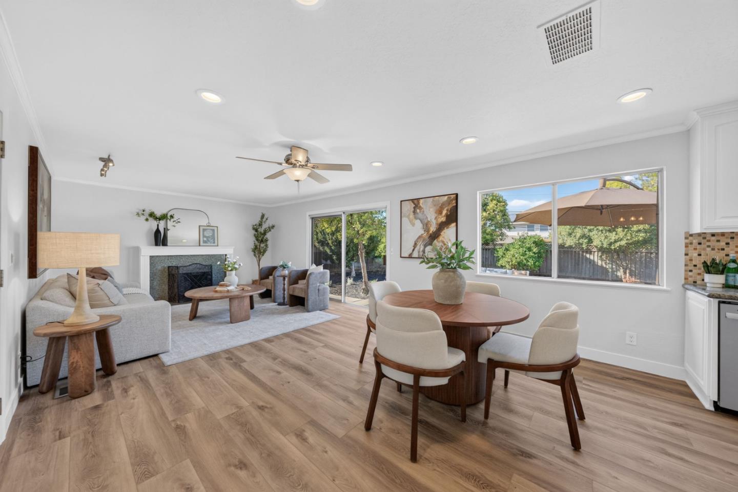 Open-plan living and dining room with a fireplace, round table, and sliding glass doors to the yard.