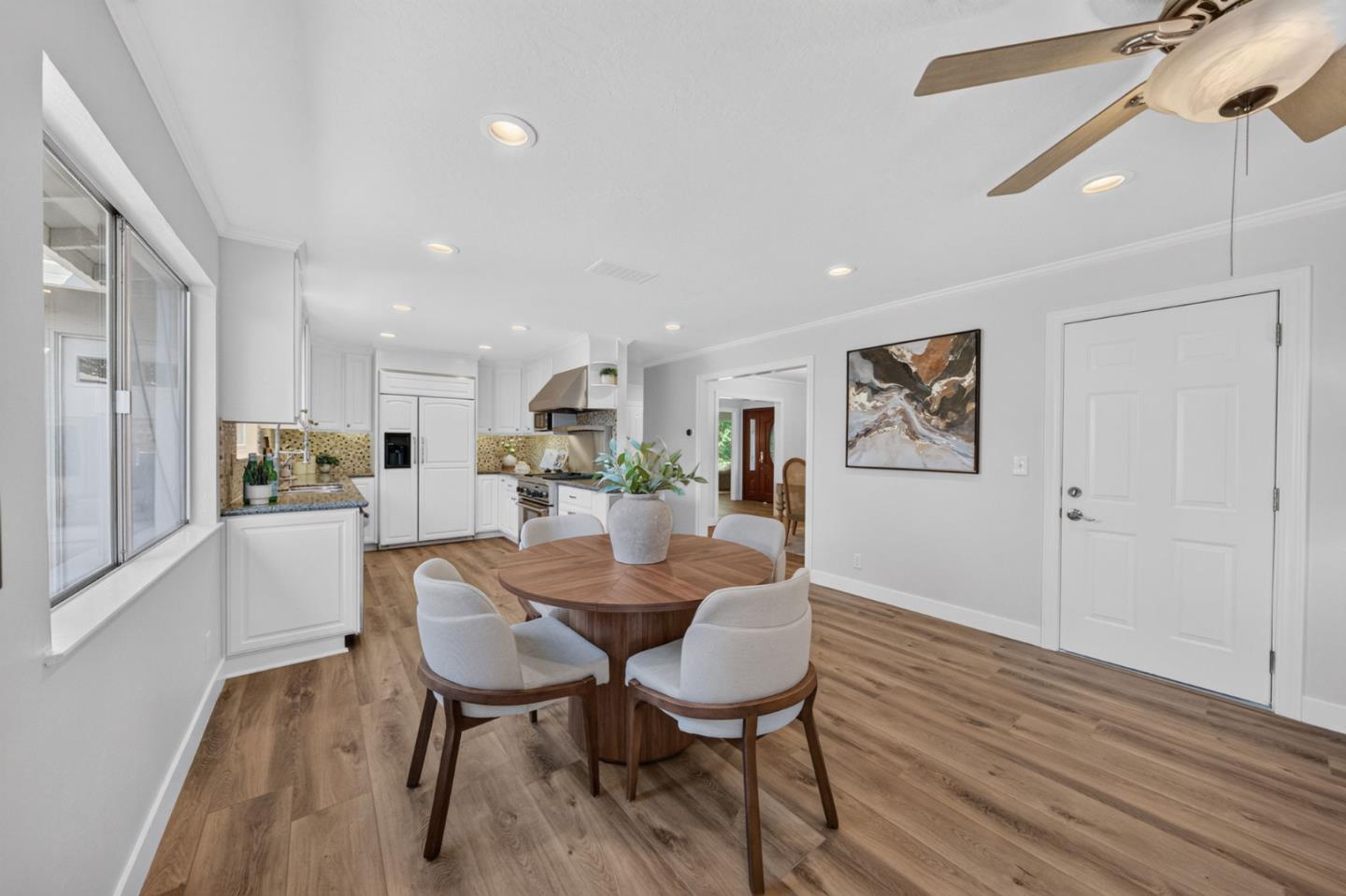 Open kitchen and dining area with white cabinetry, patterned backsplash, and a round wood table.