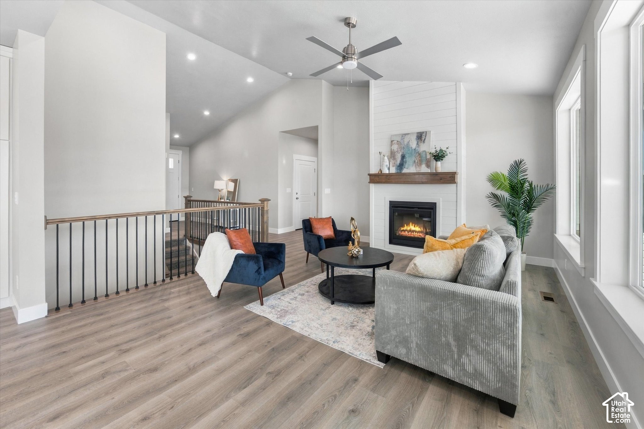 Staged living room with a white fireplace, gray sofa, navy chairs, and large windows.