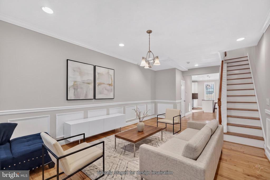 Virtually staged living room with hardwood floors, paneled walls, contemporary seating, and a staircase.