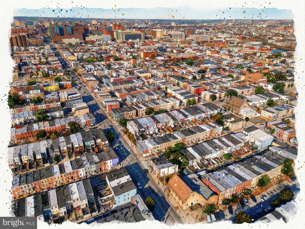 Aerial view of Baltimore row houses along a broad street, with downtown buildings in the distance.
