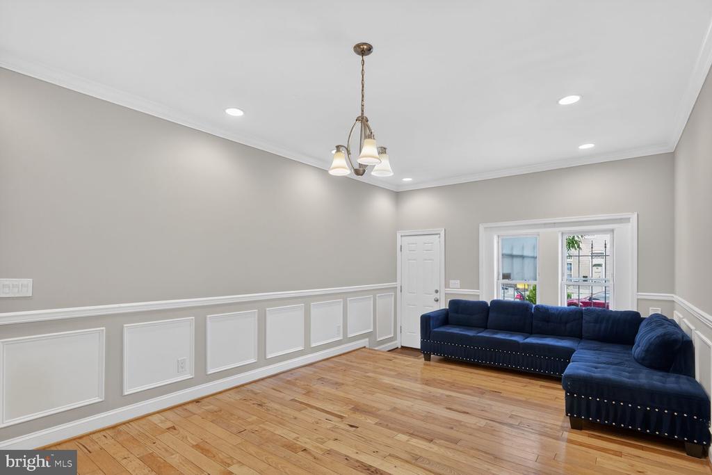 Living room with a navy L-shaped sofa, hardwood floors, and white wainscoting.