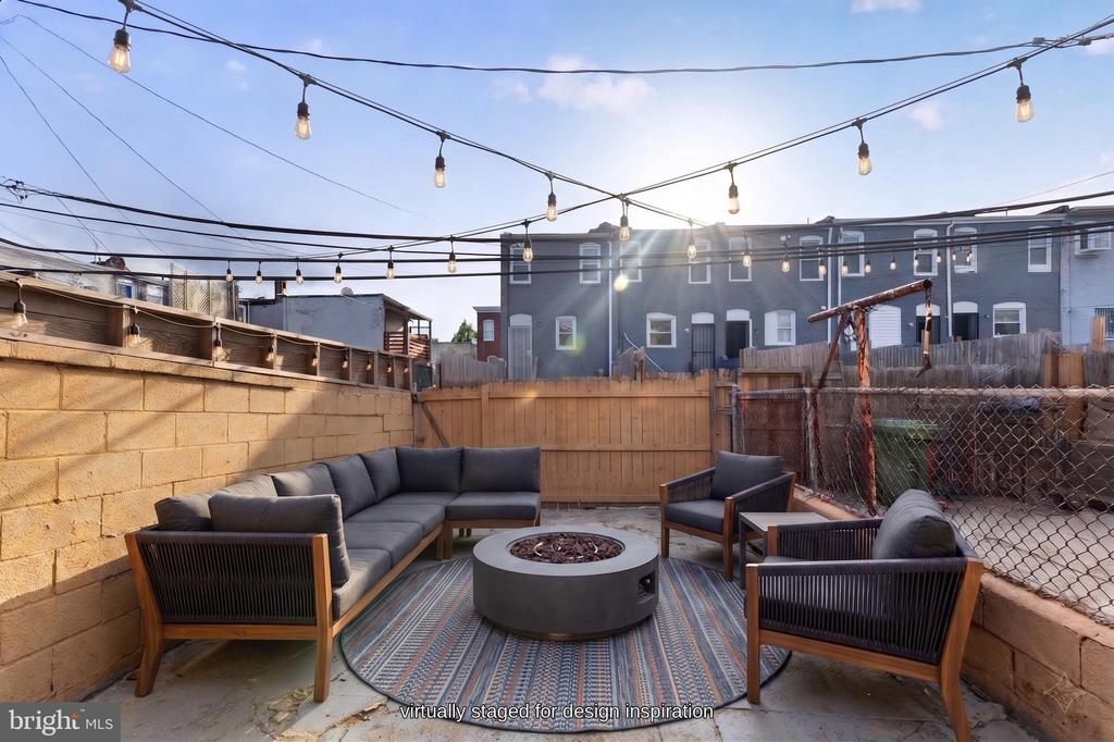 Back patio with outdoor sectional seating, round fire pit, and overhead string lights.