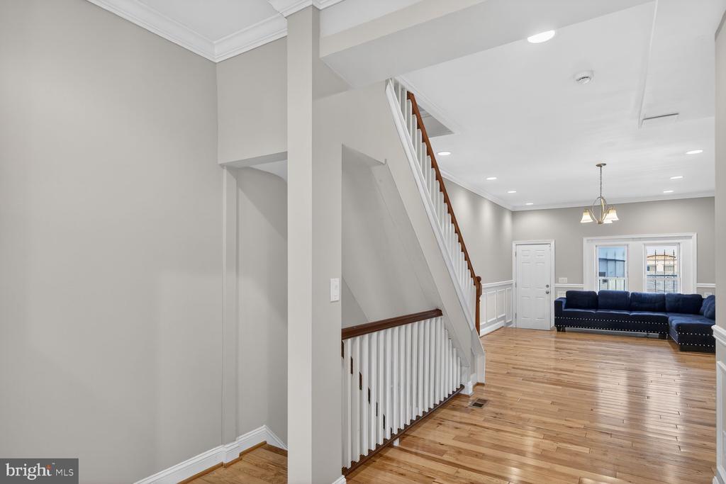 Living room with hardwood floors, a white staircase, and a dark blue sectional sofa.