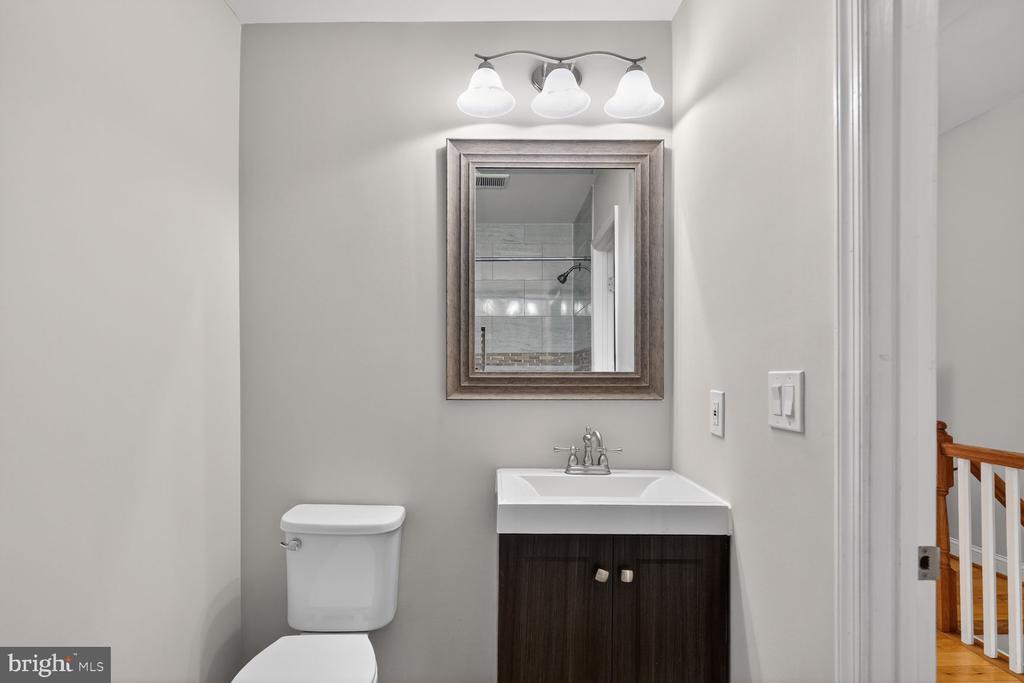 Bathroom with a dark wood vanity, framed mirror, and tiled shower reflected in the mirror.