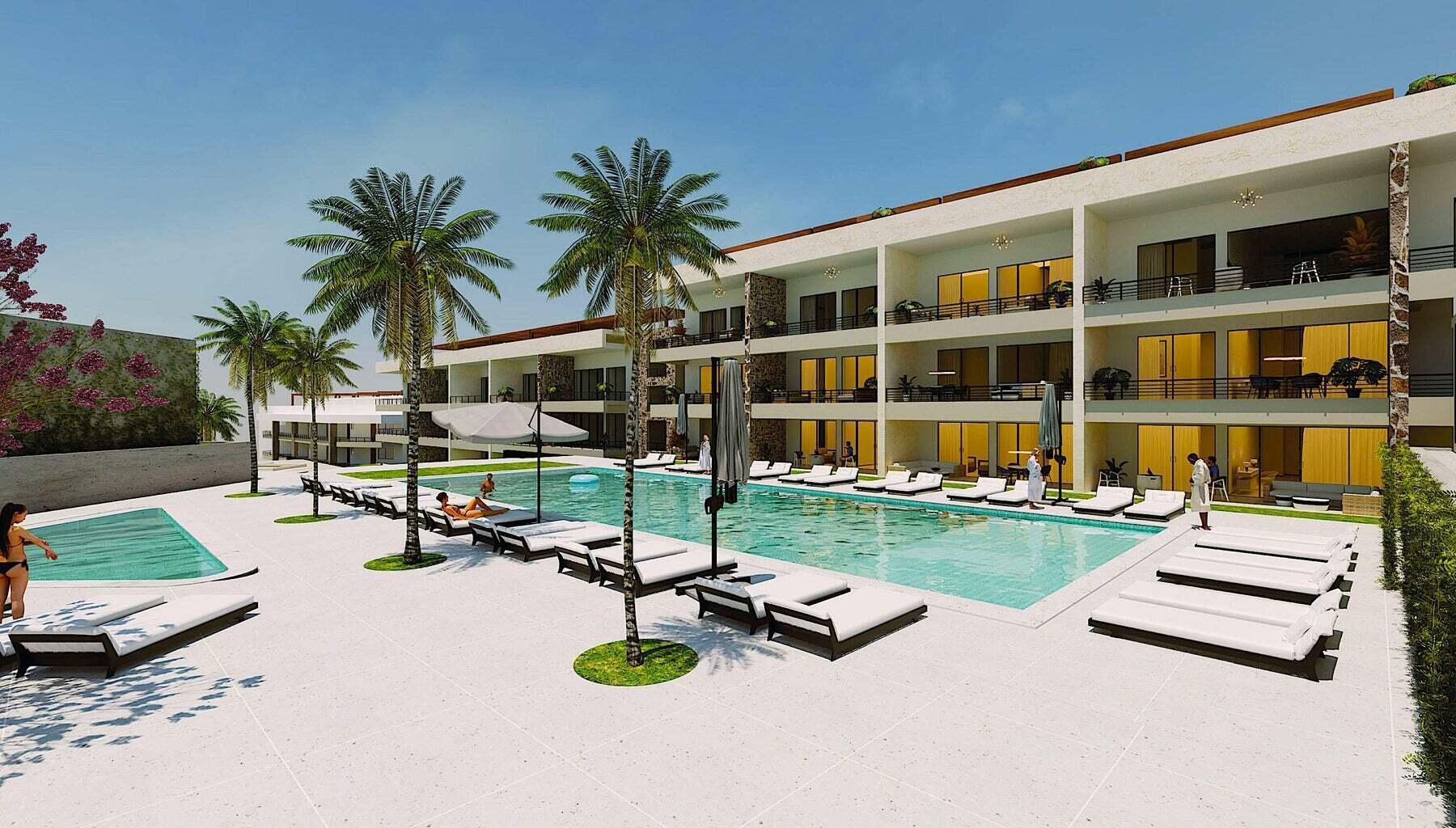 Modern condominium complex with a large pool, palm trees, and rows of sun loungers.