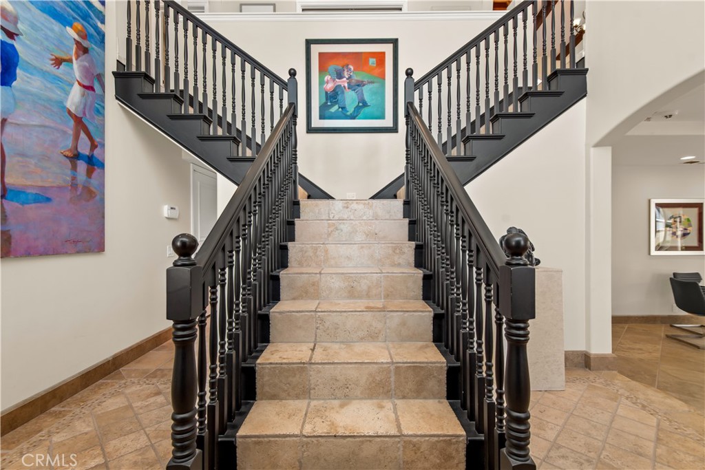 Tiled foyer staircase with ornate black railings and colorful artwork.