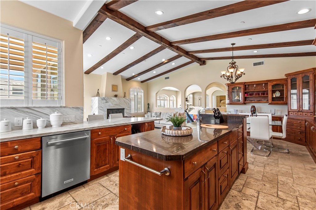 Kitchen with a large wood island, stone countertops, and exposed ceiling beams.