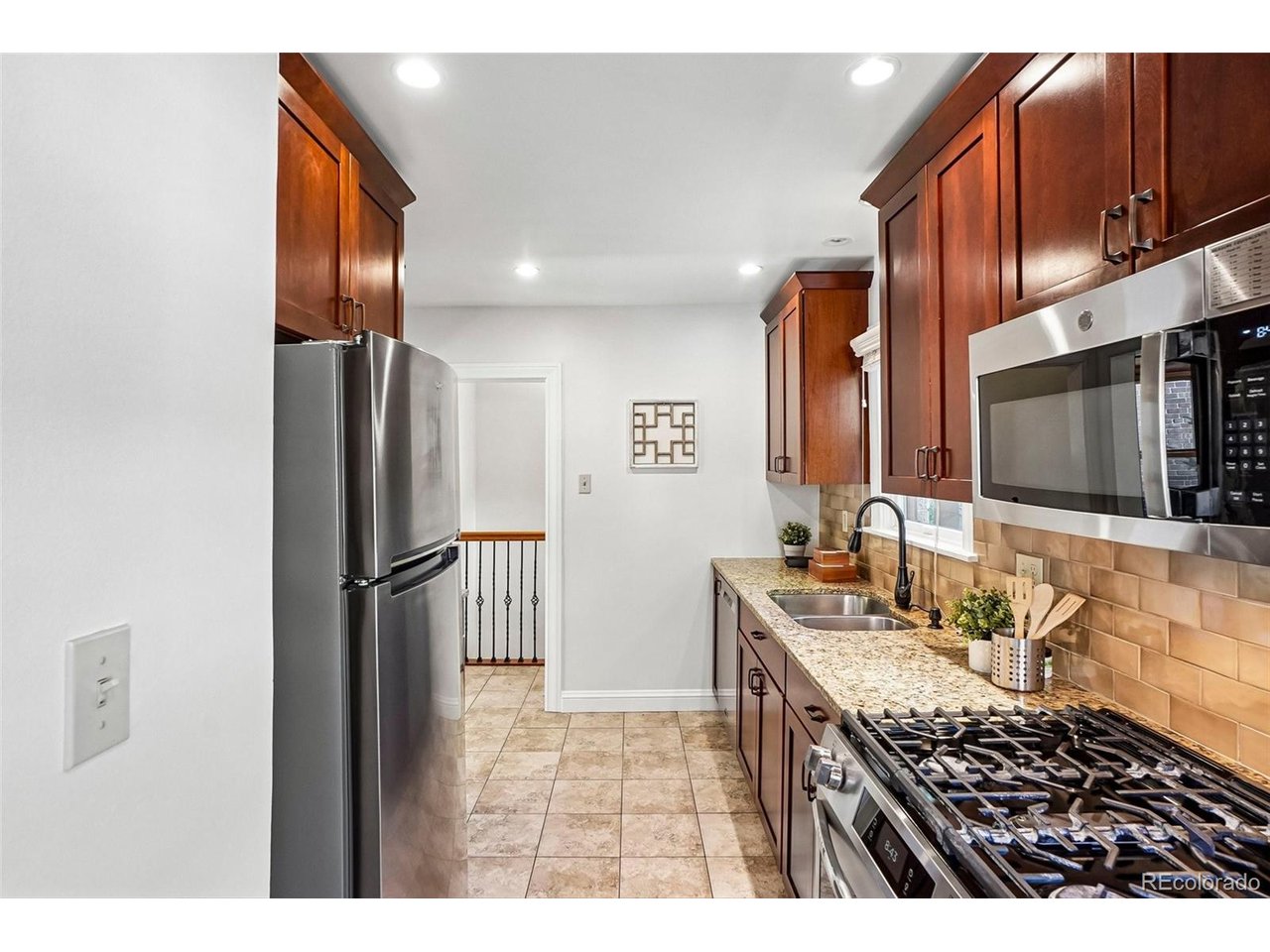Kitchen with dark wood cabinets, granite counters, stainless appliances, and a gas range.