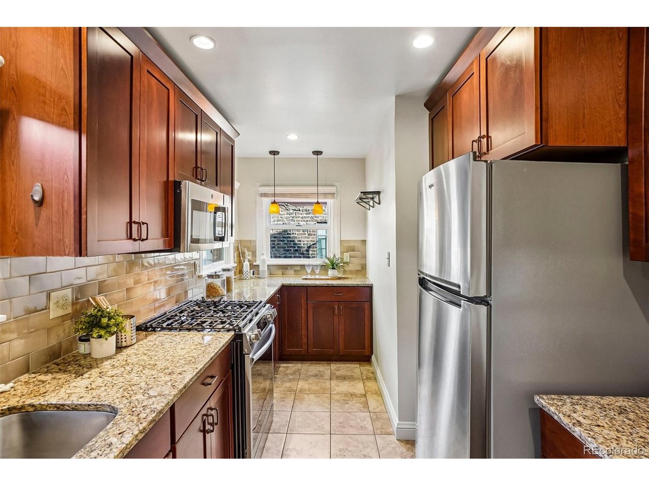 Galley kitchen with dark wood cabinets, granite counters, and stainless steel appliances.