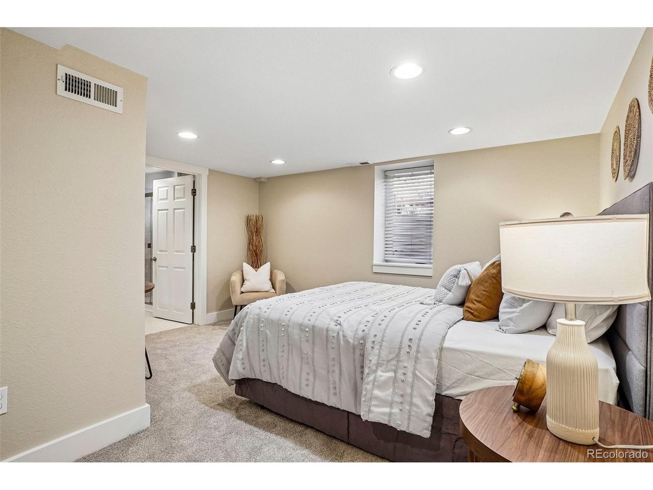 Furnished bedroom with a white bed, accent pillows, and a small armchair.