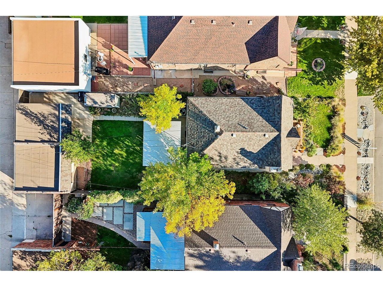 Aerial view of homes and landscaped yards, with patios, walkways, and mature trees.
