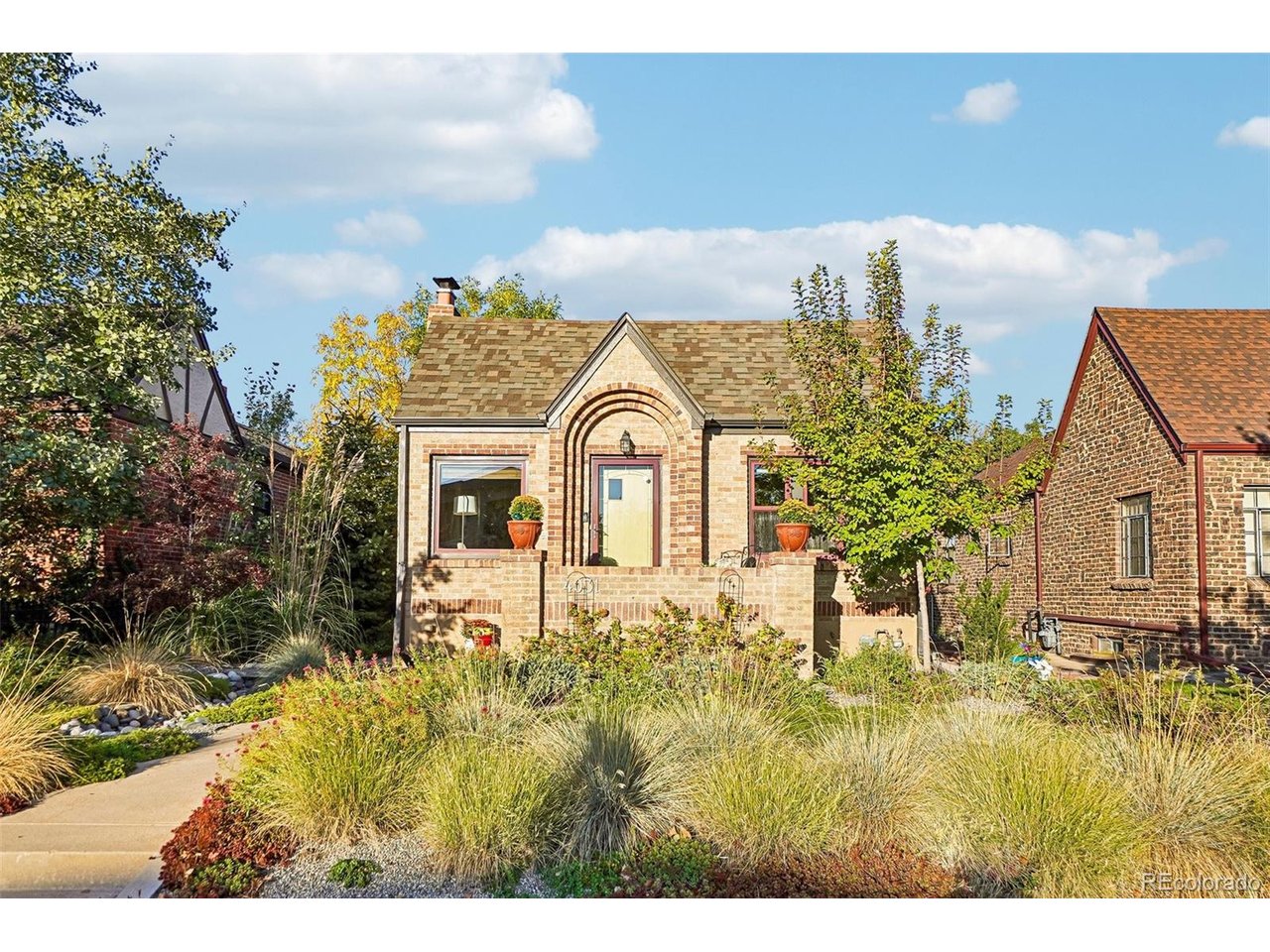 Brick house with an arched entry, low porch wall, and landscaped front garden.