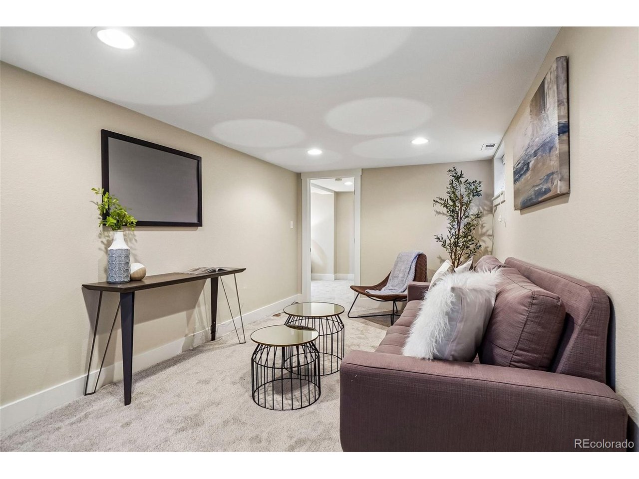 Staged basement living room with a mauve sofa and round nesting coffee tables.