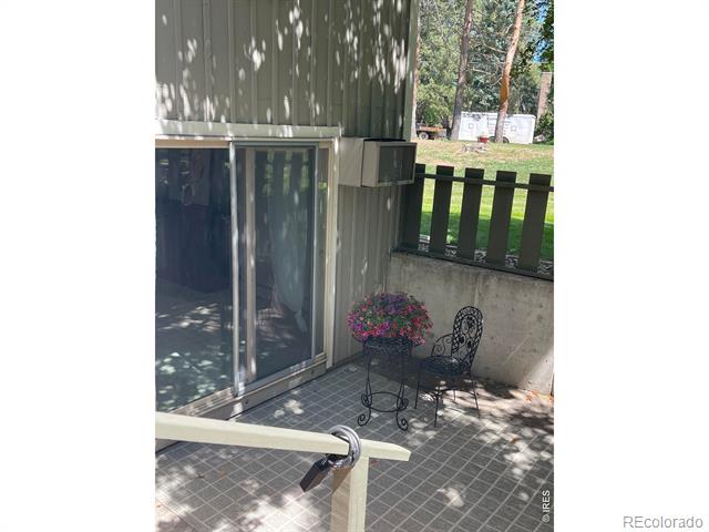 Tiled patio with wrought-iron chairs and flowers beside a sliding glass door.