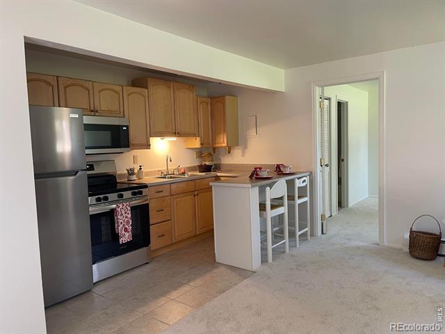 Kitchen with wood cabinets, stainless steel appliances, and a breakfast bar with stools.