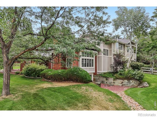 Two-story brick-and-siding home framed by mature trees, with landscaped gardens and a stone path.
