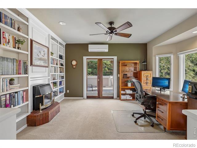 Home office with built-in bookshelves, brick fireplace, and desk beside glass doors.