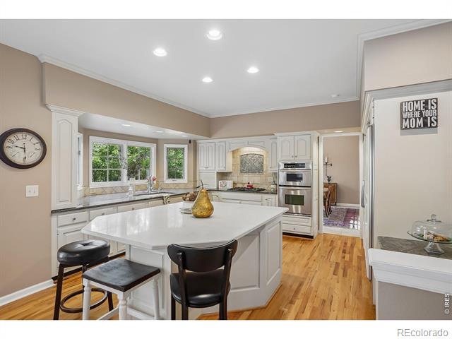 Kitchen with a large white island, stainless steel appliances, and hardwood floors.