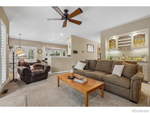 Furnished living room with a brown sectional, armchair, wooden coffee table, and glass-front display cabinets.
