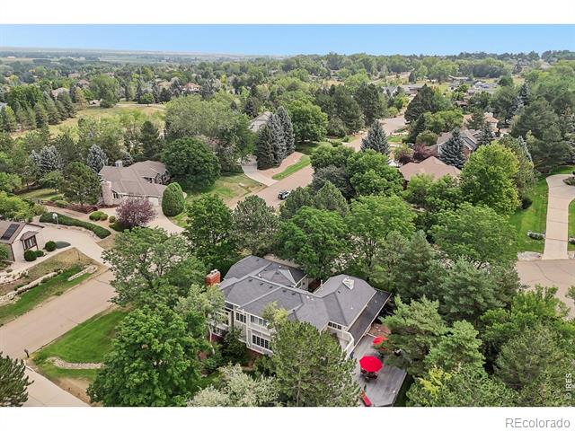 Aerial view of a gray-roofed house among mature trees and residential streets.