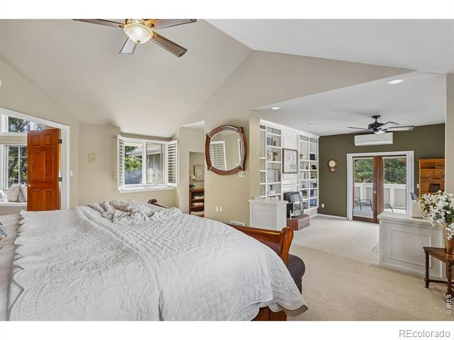 Spacious bedroom with a large bed, vaulted ceiling, and built-in shelving beside a sitting area.