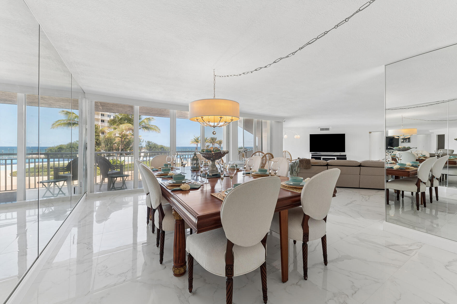 Oceanfront condo dining area with a set table, mirrored walls, and ocean views.