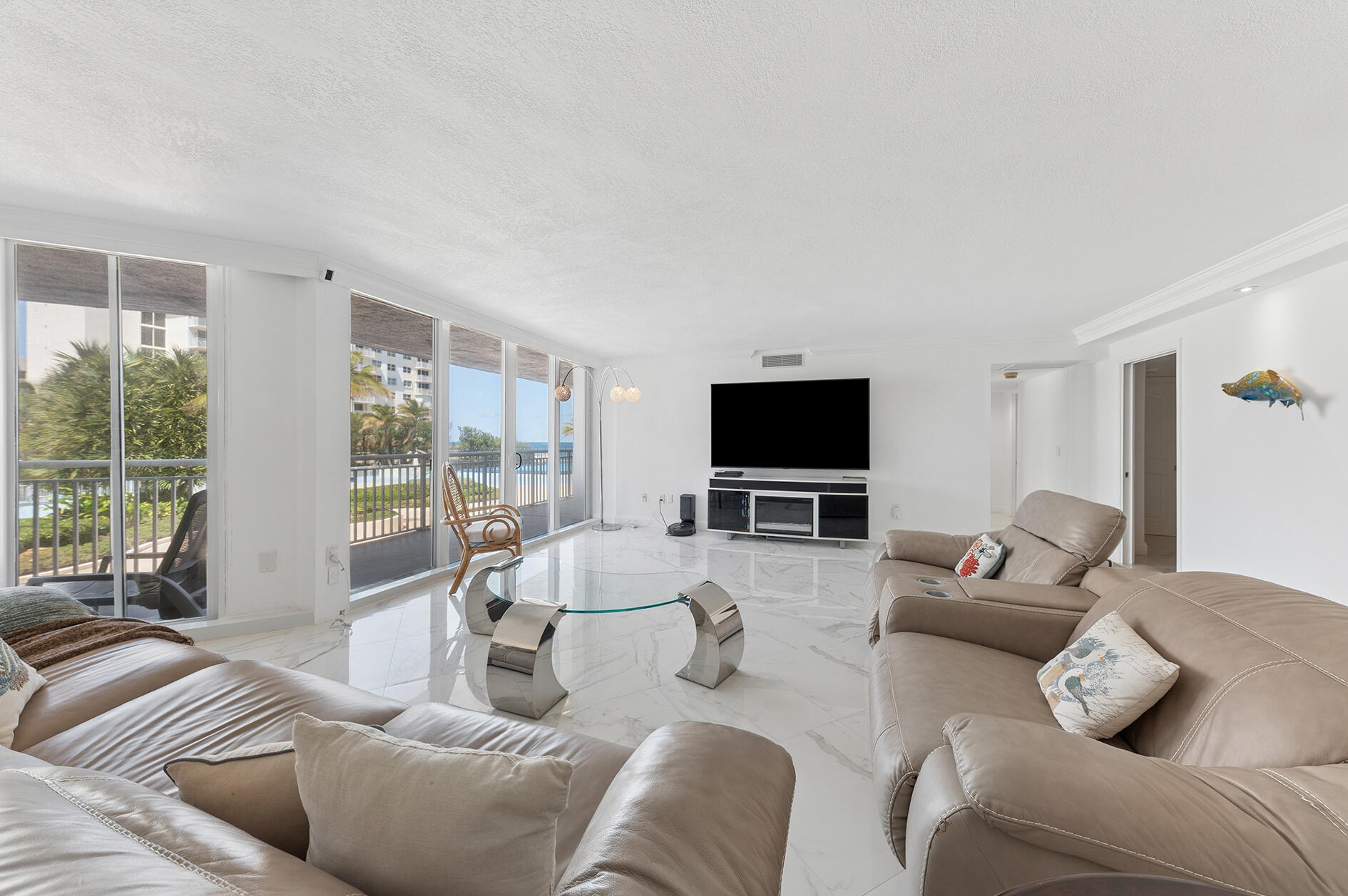 Living room with leather sofas, marble floors, and sliding doors overlooking the ocean.