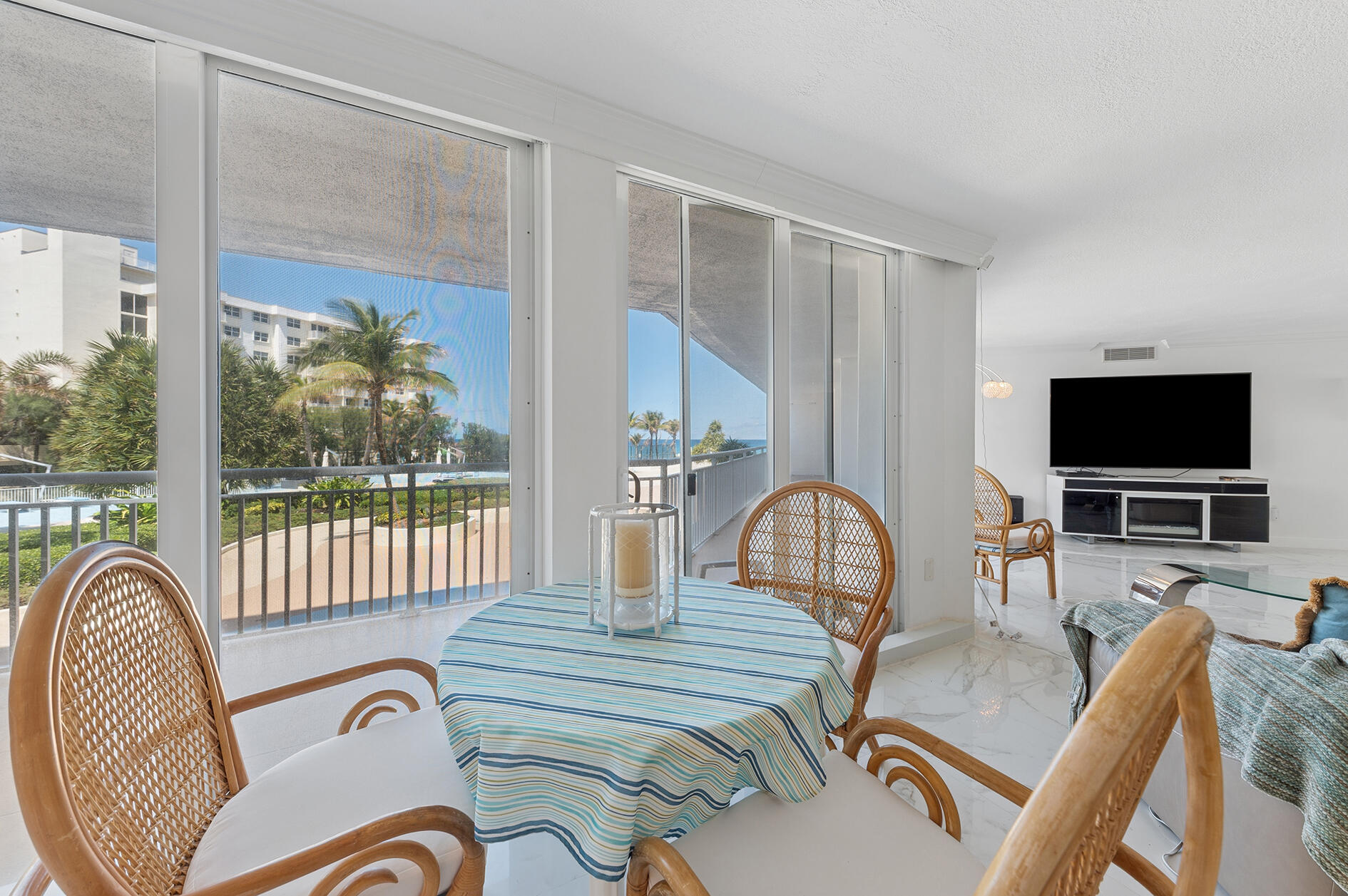 Dining area with wicker chairs and sliding glass doors opening to a balcony with ocean views.
