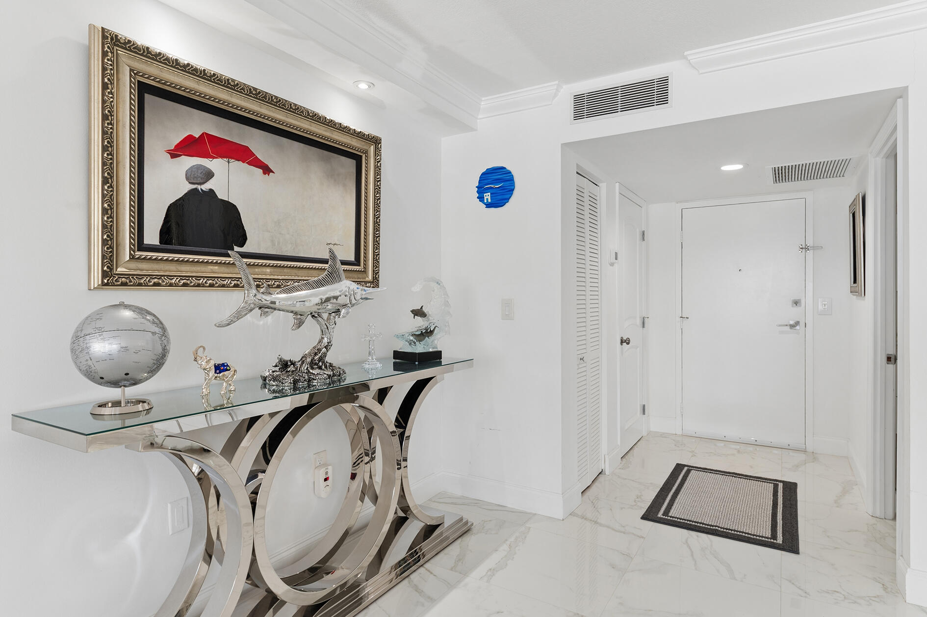 Bright condo foyer with marble flooring, a mirrored console table, and framed artwork.