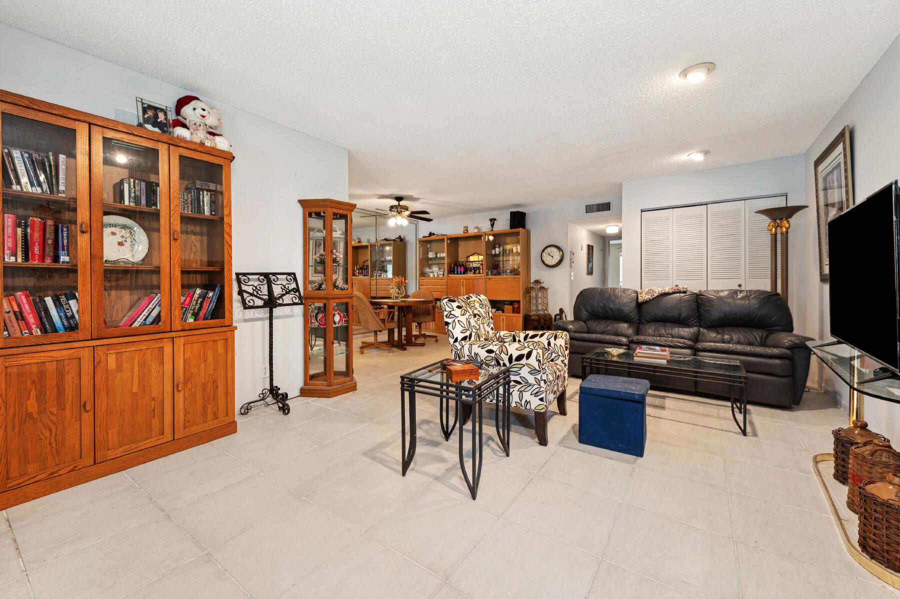 Living room with a black leather sofa, patterned chair, and large wooden display cabinets.