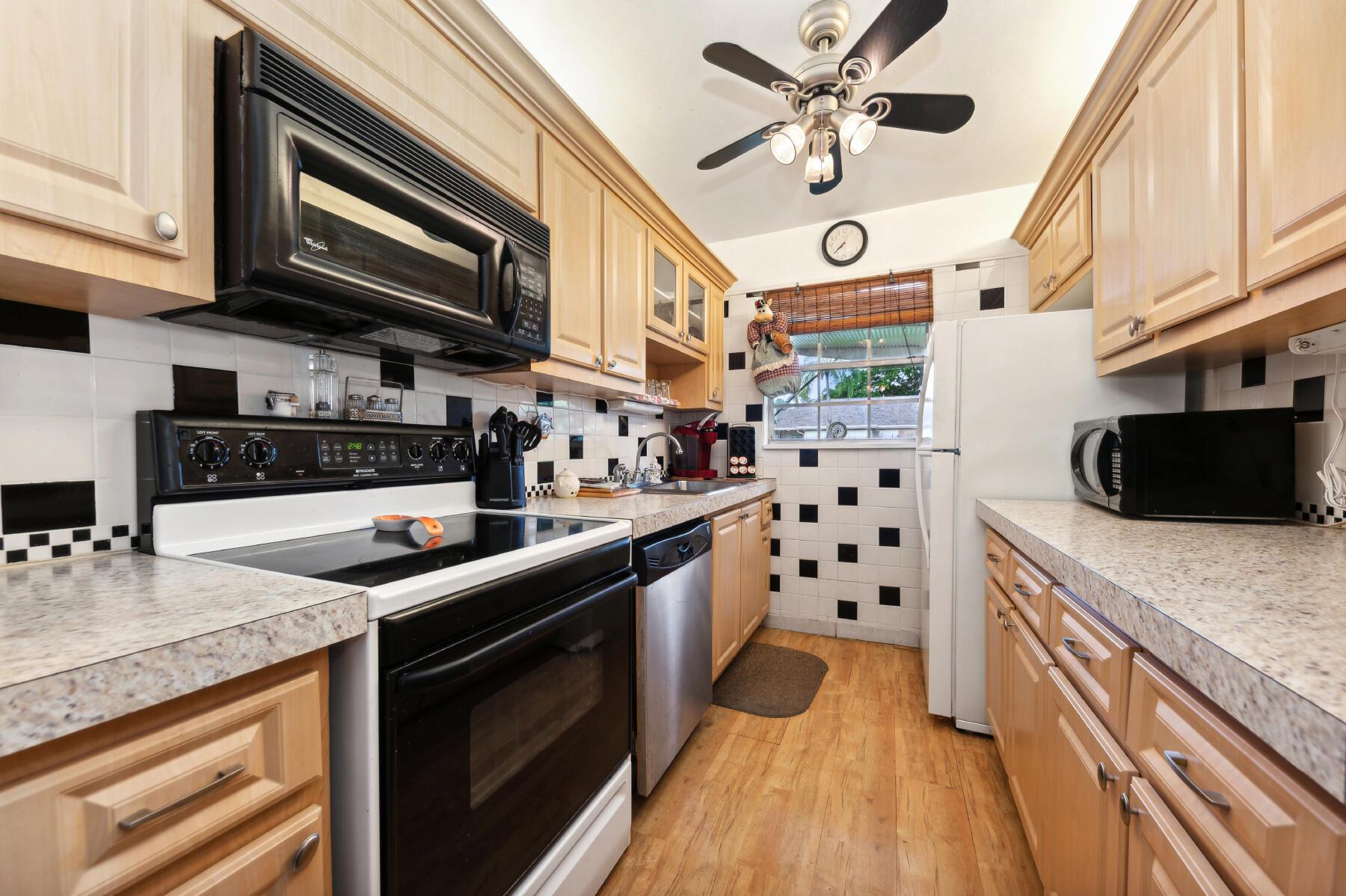 Kitchen with light wood cabinets, black-and-white tile, and a window above the sink.