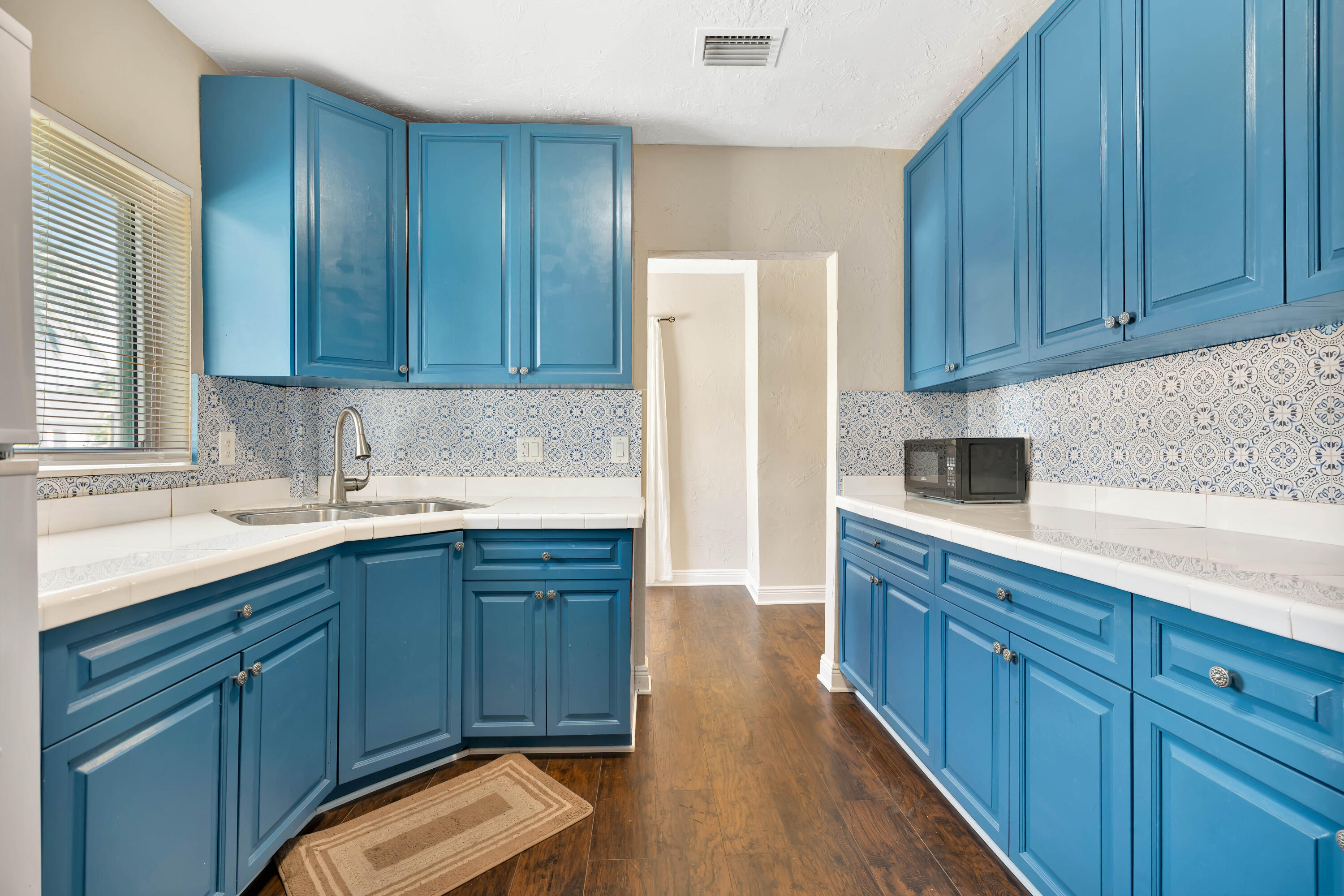 Kitchen with blue cabinets, patterned tile backsplash, and white countertops.