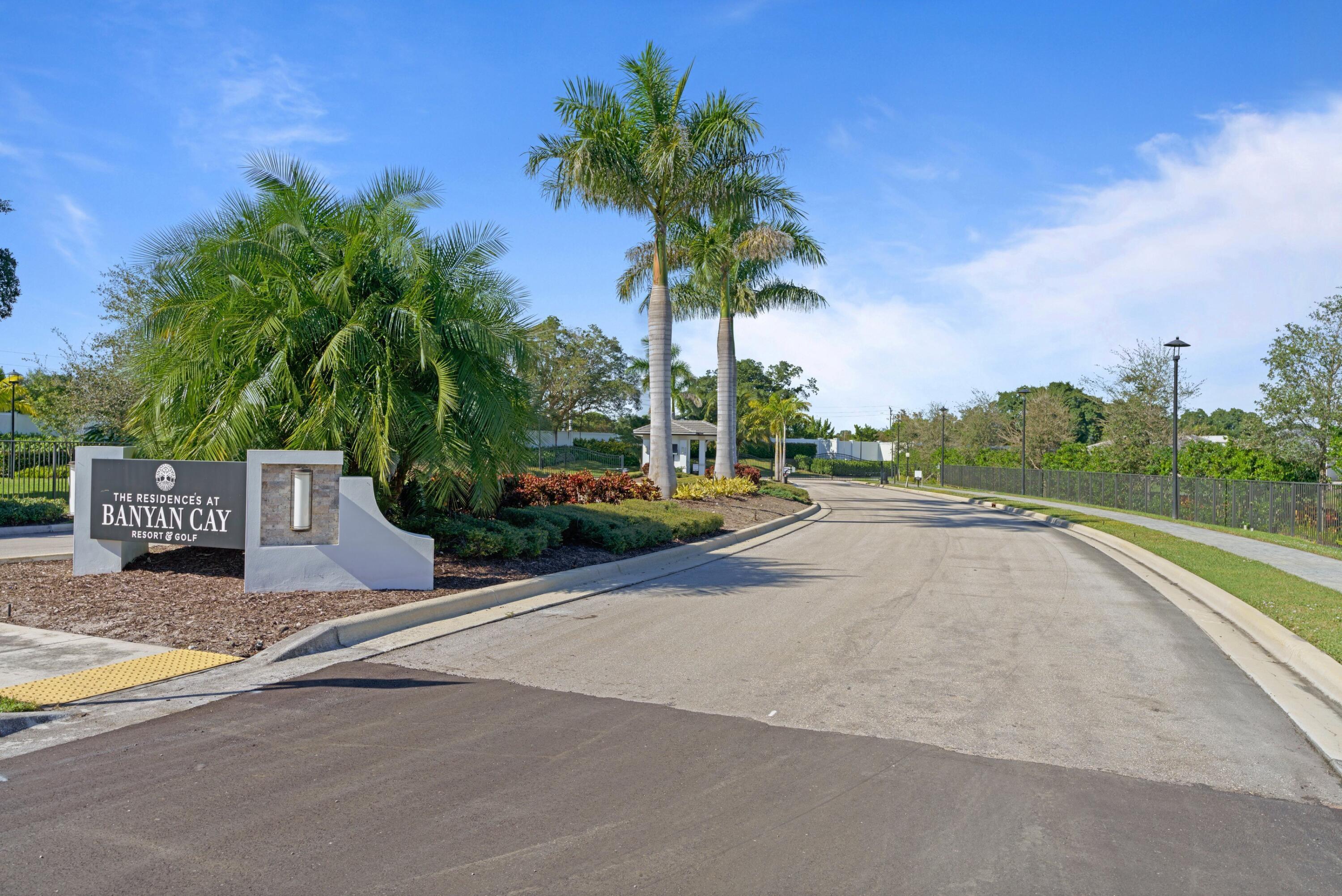 Banyan Cay community entrance sign beside palm trees and a landscaped roadway.