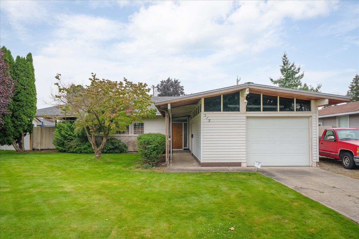 Single-story home with clerestory windows, attached garage, and broad green lawn.