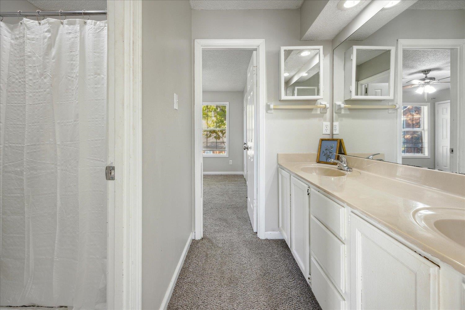 Bathroom with a long white double-sink vanity, mirrored cabinets, and a shower curtain.
