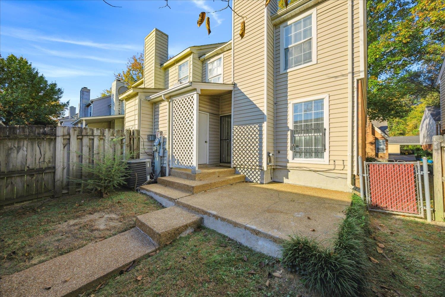 Rear exterior with a concrete patio, lattice panels, and a fenced yard.
