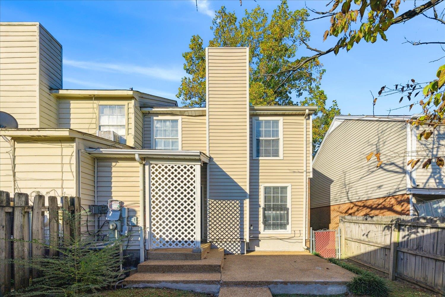 Rear exterior of a beige-sided home with a lattice-covered porch and concrete patio.
