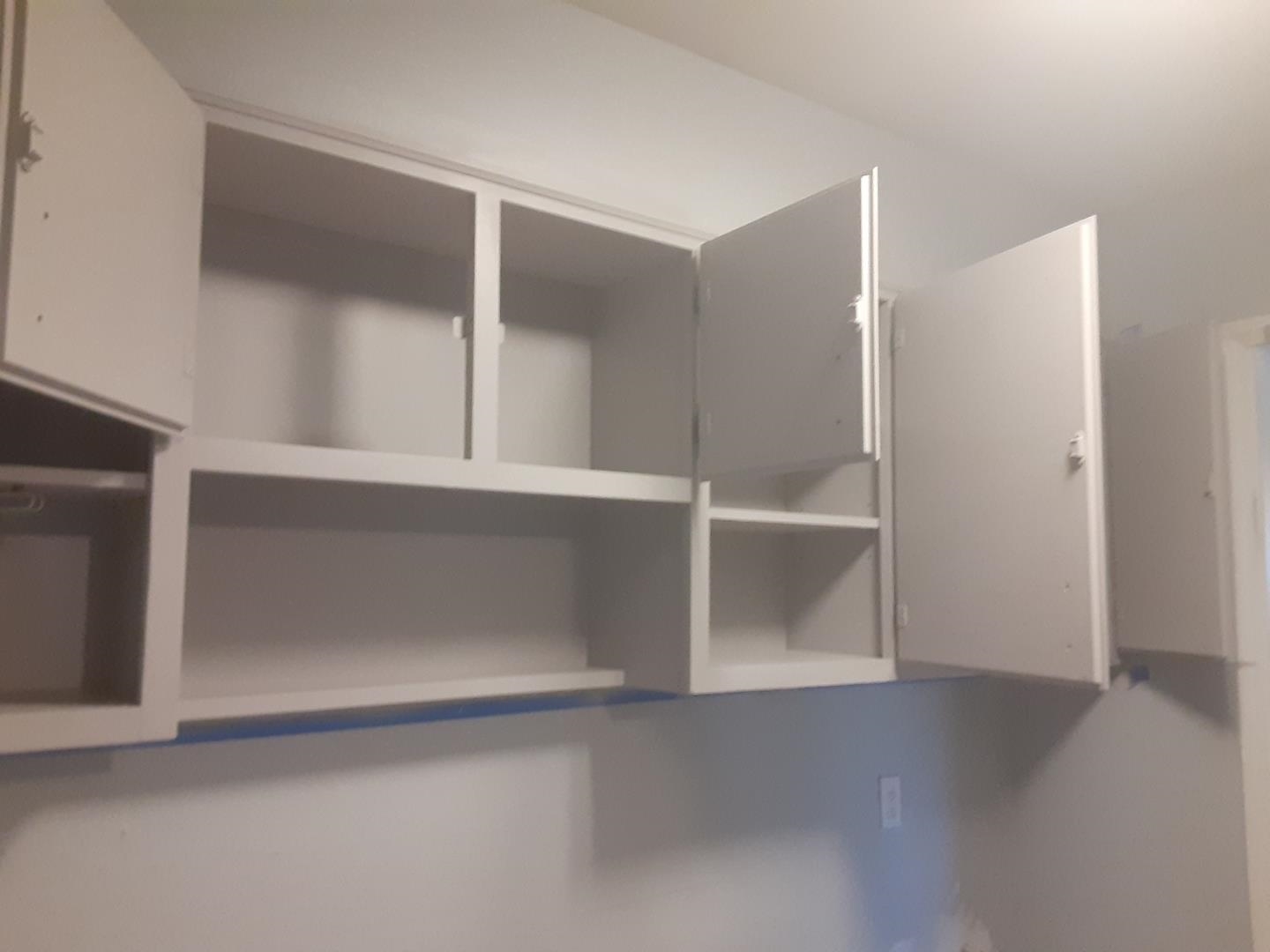 Built-in closet with open white cabinets, empty shelves, and a hanging rod.
