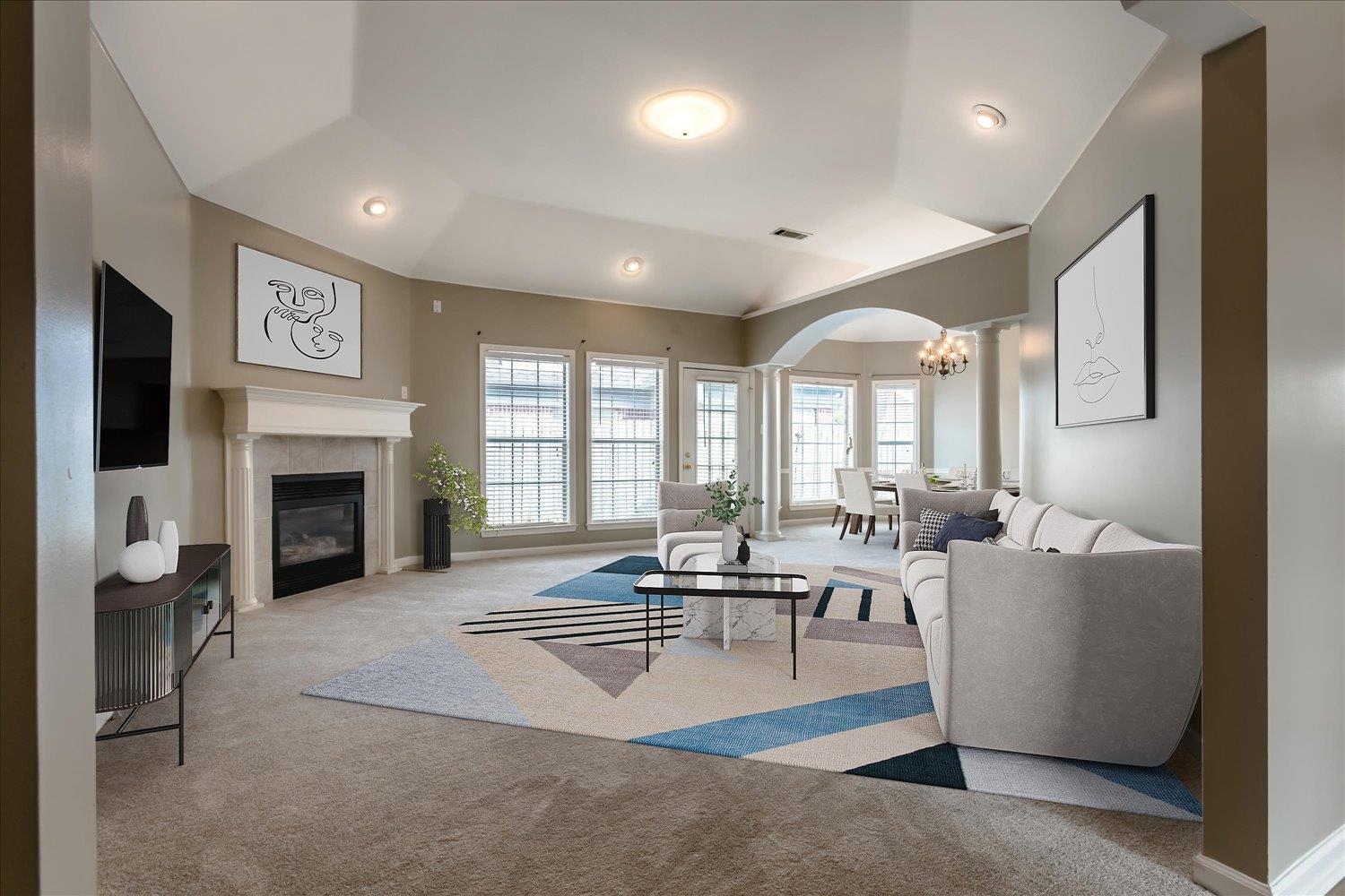 Living room with a vaulted ceiling, fireplace, white sectional, and adjoining dining area.