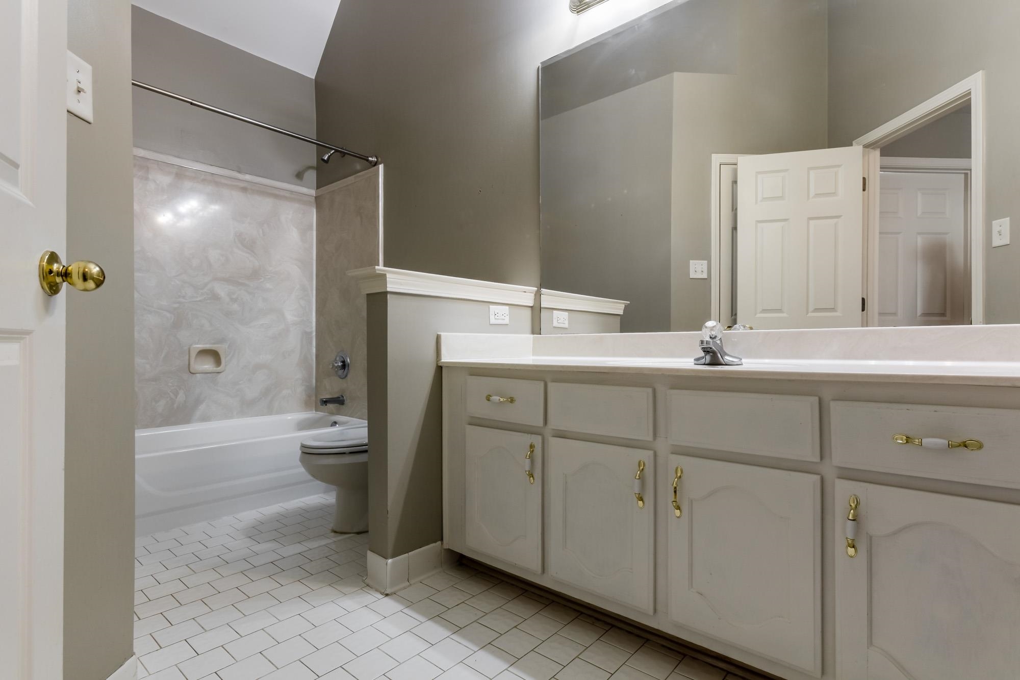 Bathroom with a long white vanity, large mirror, and tiled tub-shower.
